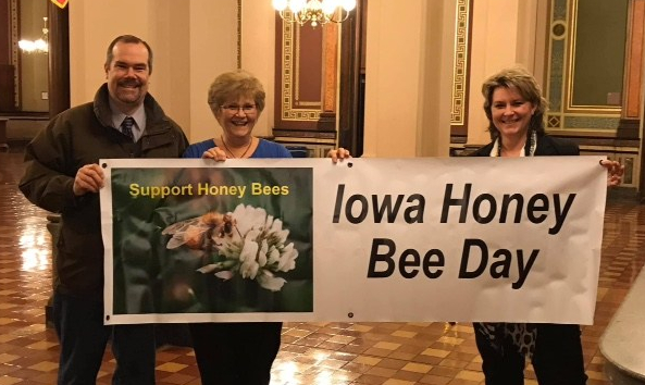 three people holding Iowa Honey Bee Day sign